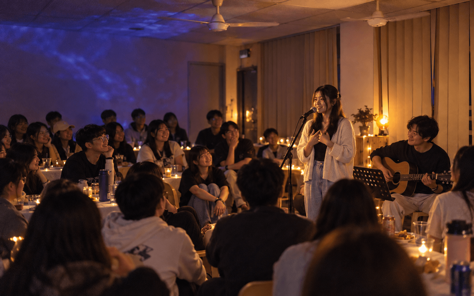 年轻人围坐在温暖灯光下，听演唱者分享一首歌的故事
